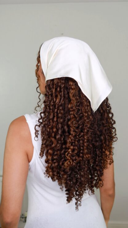 Silky satin hair scarf being worn in bandana style on long curly hair